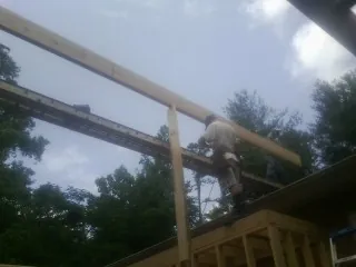 Carpenter setting a ridge beam over a new addition frame — Ice Dam Removal by Roofing Brothers in Herscher