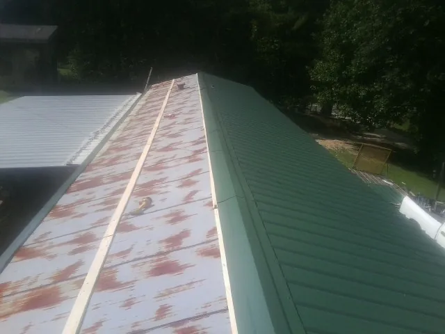 Old rusted panels beside newly installed green metal roofing — Wind Damage Roof Repair by Roofing Brothers in Herscher