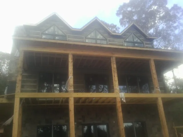 Dormers and porch framing on a large log home under construction — Roof Coating work by our crew in Herscher