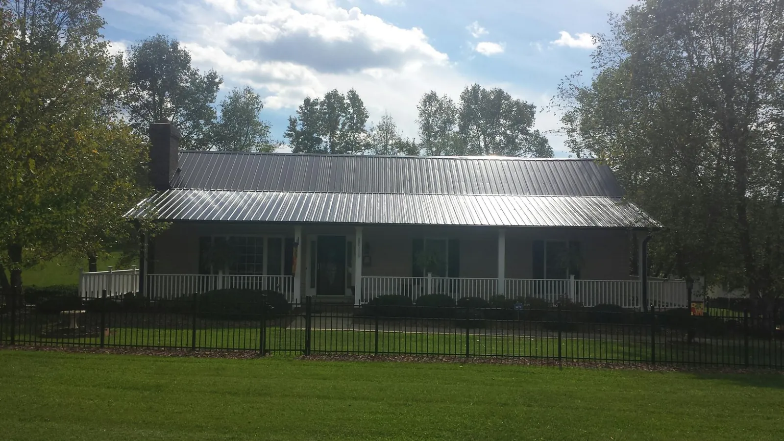 Gray metal roof on a brick ranch with a full width front porch — Gutter Guard Installation work by our crew in Herscher